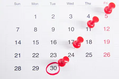 A calendar with red push pins marking dates
