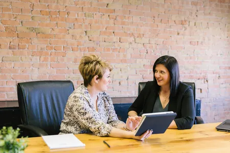 Two colleagues talking at a table with a tablet