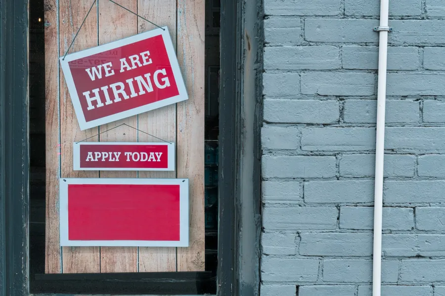 A we are hiring sign on a brick wall