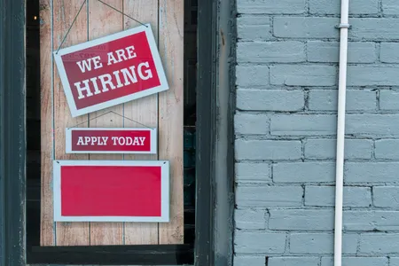 A we are hiring sign on a brick wall