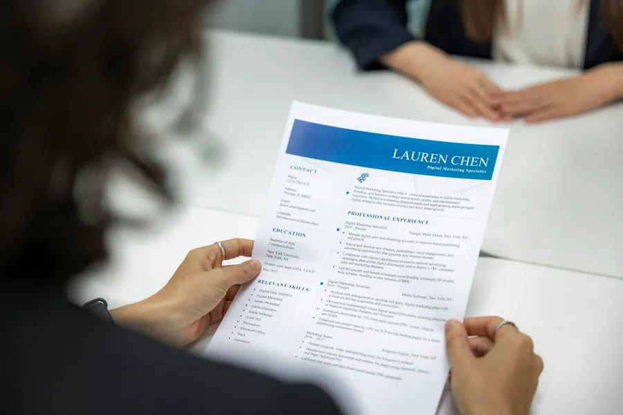 A person reading a printed resume at a table