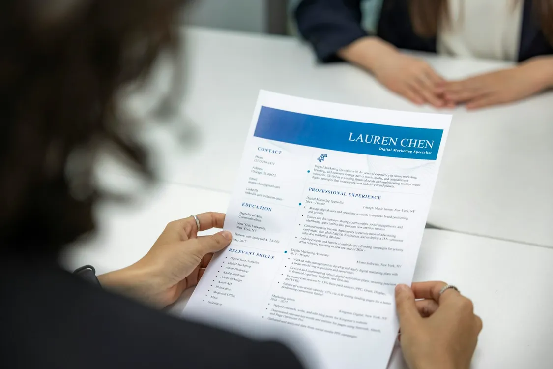 A person reading a printed resume at a table