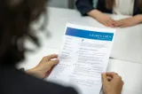 A person reading a printed resume at a table