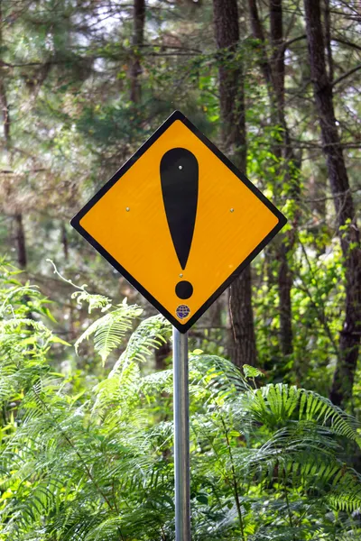 A yellow warning sign in a forest
